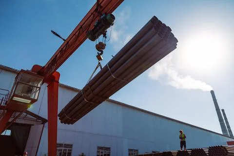 Gantry crane transporting stack of metal pipes Stock Photos