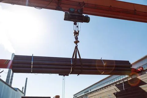 Gantry crane transporting stack of metal pipes Stockfoto's
