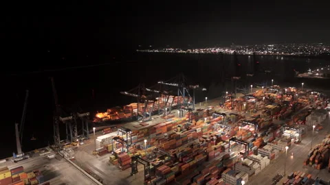 Gantry cranes loading and unloading intermodal cargo containers from a docked Stock Footage 345525692
