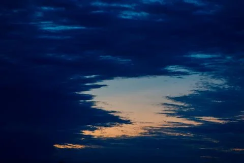 Gap in dark blue clouds with orange sunset sky in Argentina Stock Photos