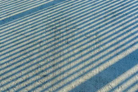 Gap step diagonal shadows from sunlight on a scratched concrete surface Stock Photos