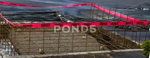 Gaping hole in concrete surrounded by red construction danger barrier Stock Photos