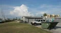 Garage Building Next To Dumpster In Parking Lot With Clouds HD Video HD