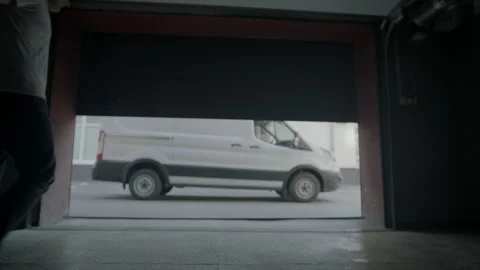 Garage door is going up and man is carrying cases on cargo cart to the truck Stock Footage 222561093