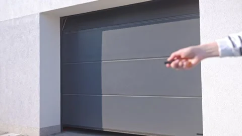 Garage door opening while hand presses remote control outside house Stock Footage 333536171