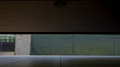 Garage door opens from an interior view to a fenced yard Stock Footage 333652839