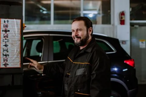 In the garage mechanic guy looking at the camera he is fixing the car and Stock Photos