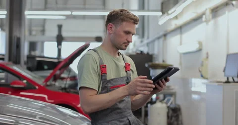 In a garage a mechanic using the tablet makes the oil and engine check Stock Footage 341868935