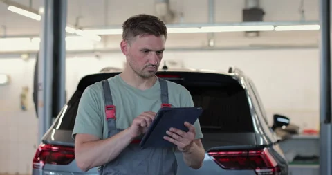 In a garage a mechanic using the tablet makes the oil and engine check Video stock 341869258