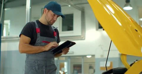 In a garage a mechanic using the tablet makes the oil and engine check to the Foto stock
