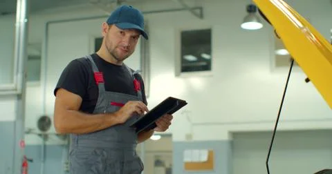 In a garage a mechanic using the tablet makes the oil and engine check to the Foto stock