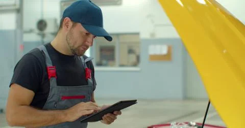 In a garage a mechanic using the tablet makes the oil and engine check to the Foto stock