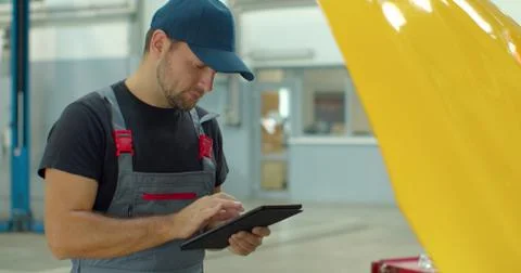 In a garage a mechanic using the tablet makes the oil and engine check to the Foto stock