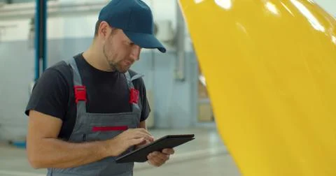 In a garage a mechanic using the tablet makes the oil and engine check to the Foto stock