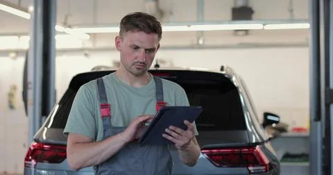 In a garage a mechanic using the tablet makes the oil and engine check to t.. Stock Photos