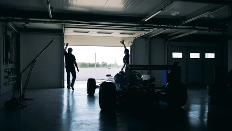 Garage with a racing car inside is getting closed by two men Stock Footage 165197644