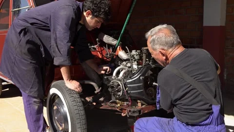 Garage setup showcasing teamwork repairing vintage motor components Stock Footage 309239906