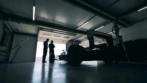 Garage with two men talking while observing a racing car Video stock 159787893