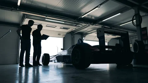 Garage unit with a racing car and two mechanics Stock Footage 162877698