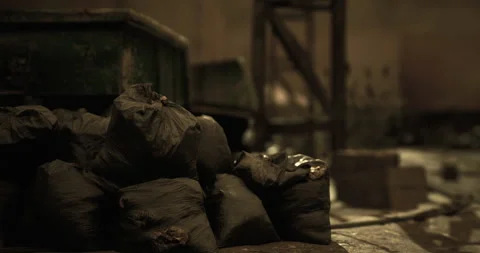 Garbage bags piled in a dimly lit abandoned warehouse setting Stock Footage 321823879