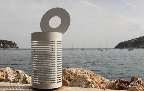 Garbage bin on the beach against the background of the sea. Stock Photos