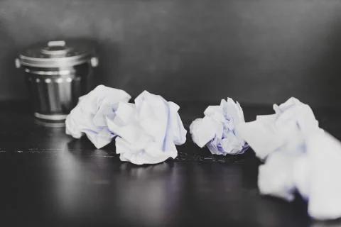 Garbage bin on desk setting and scrunched paper balls Stock Photos