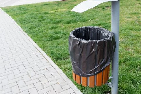 A garbage bin with a garbage bag is installed in a public place. Located cl.. Stock Photos