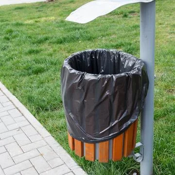 A garbage bin with a garbage bag is installed in a public place. Located cl.. Stock Photos
