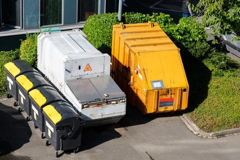 Garbage cans and large containers standing in the yard of the house. Stock Photos