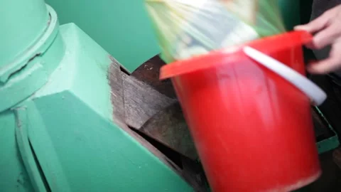 The garbage chute in the house. A man throws waste in a red bucket into a ga Stock Footage 230985584