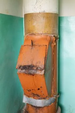 The garbage chute is situated in an aged building with a distinctive color sc Stock Photos