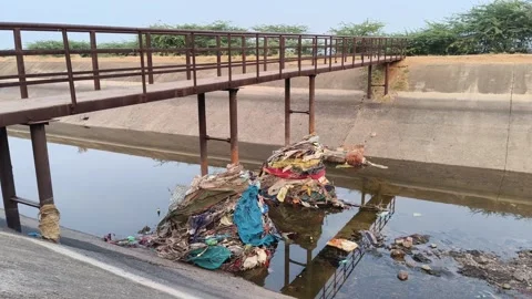 Garbage collected beneath a small bridge in a drainage canal Stock Footage 327982274