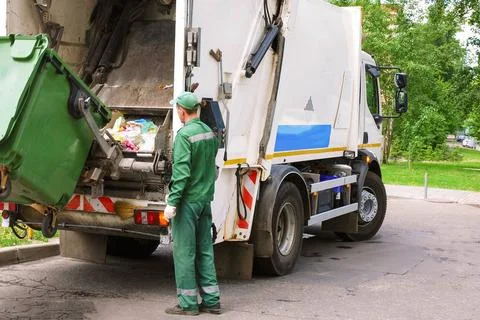 Garbage collection worker operating garbage compressor track in residentia... Stock Photos
