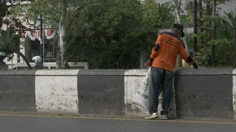 Garbage collector in uniform picking up waste or litter Stock Footage 137421520