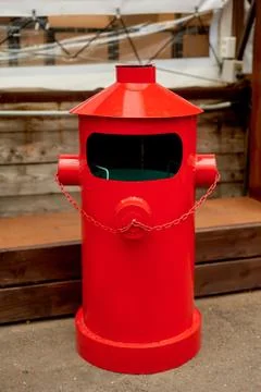 The garbage container is metallic red in a loft-style space on the street Stock Photos