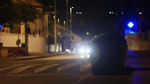 Garbage container at night, with a car and a lighted medical clinic sign in the Stock Footage 328390953