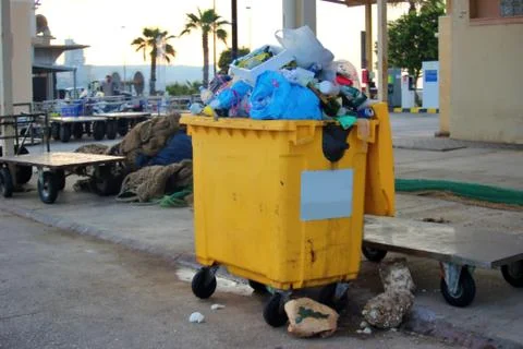Garbage container overflowing with plastic bags and trash Stock Photos