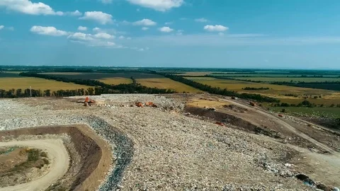 Garbage dump on the background of green fields. Garbage disposal equipment goes Vídeos de archivo 114495130