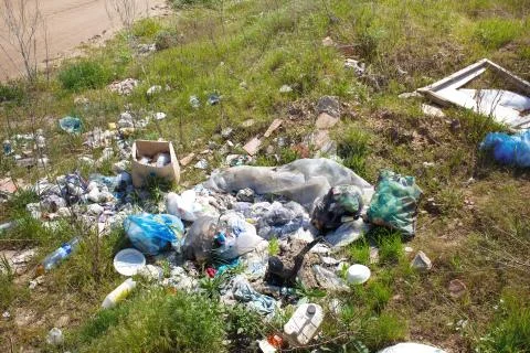 Garbage dump on the grass next to a sand road closeup Stock Photos