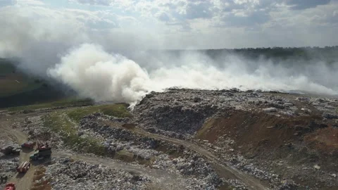 Garbage dump pollutes the environment. Strong wind rises toxic smoke of burning Stock Footage 89690096