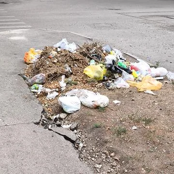A garbage dump on the side of the road with broken asphalt 스톡 사진