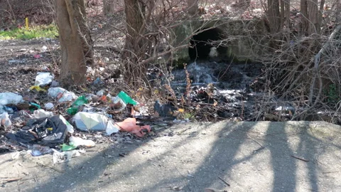 Garbage dumped on the ground near the source of the stream with running water Stock Footage 149000186