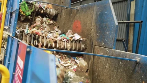Garbage falls along a trash shredder for recycling at a waste disposal factory Stock Footage 246771149