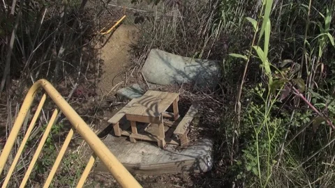 Garbage fence homeless poor table wood yellow mattress cane countryside Stock Footage 333581026