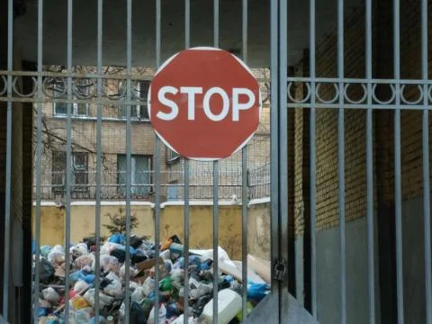 Garbage heap in the yard behind closed gates Stock Photos