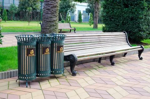 Garbage iron lattice bins for sorting garbage in a city park next to a bench. Stock Photos