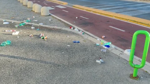 Garbage left on the bike path and roadway after a summer evening on the seafront Stock Footage 344059659