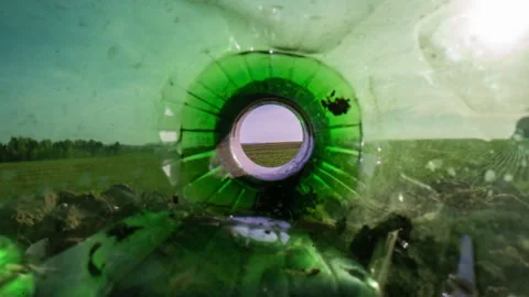 Garbage lies in the field, the camera pans over a plastic bottle, showing a Stock Footage 240907435