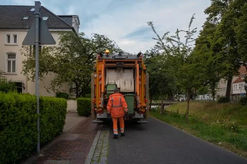 Garbage man loads garbage cans into a garbage truck Stock Photos