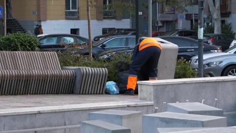 Garbage man takes out the trash from the modern style garbage bin in city park. Vidéo 256448539